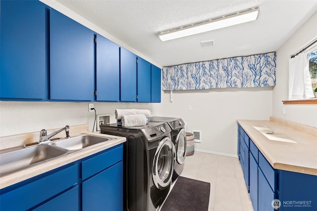 washroom with cabinet space, independent washer and dryer, a textured ceiling, and light tile patterned floors