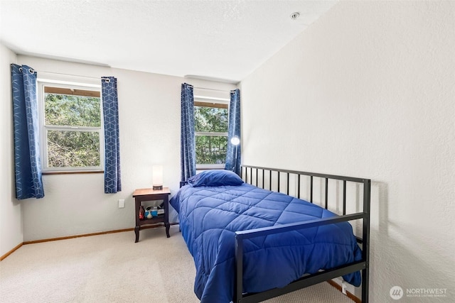 carpeted bedroom with baseboards and a textured wall