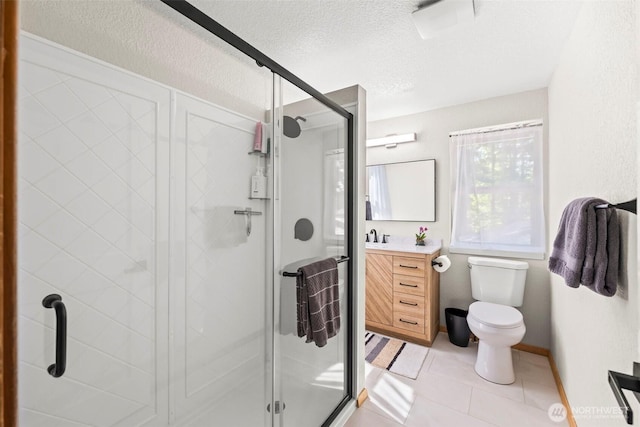 bathroom featuring vanity, toilet, a stall shower, a textured ceiling, and tile patterned floors