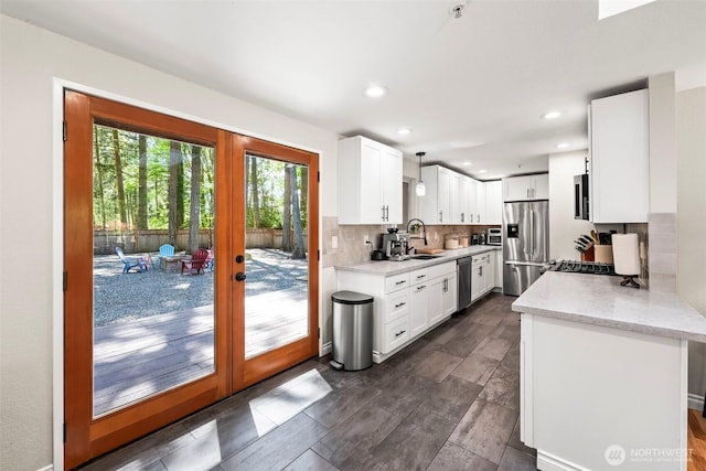 kitchen featuring stainless steel appliances, french doors, a sink, white cabinets, and tasteful backsplash