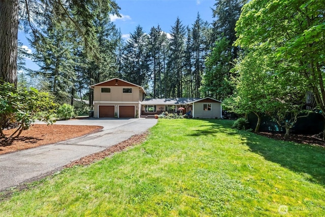 view of front facade with a garage, asphalt driveway, and a front lawn