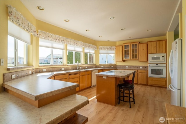 1701 E Burr Ave Unit 12, Moses Lake, WA 98837 - kitchen featuring white appliances, a kitchen breakfast bar, a peninsula, glass insert cabinets, and a sink