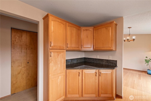 920 11th St NE, East Wenatchee, WA 98802 - kitchen with dark stone countertops, a chandelier, baseboards, pendant lighting, and a textured ceiling