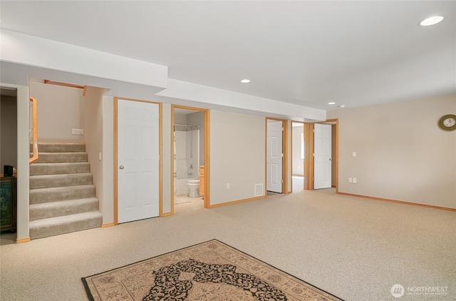 finished basement featuring visible vents, baseboards, recessed lighting, light colored carpet, and stairs