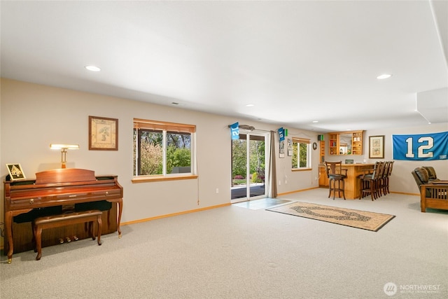 sitting room featuring baseboards, carpet, a dry bar, and plenty of natural light