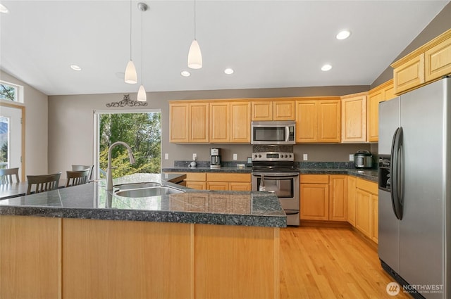 kitchen featuring light brown cabinets, tile counters, a sink, light wood-style floors, and appliances with stainless steel finishes