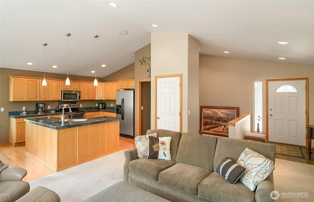 kitchen with stainless steel appliances, vaulted ceiling, a sink, and open floor plan