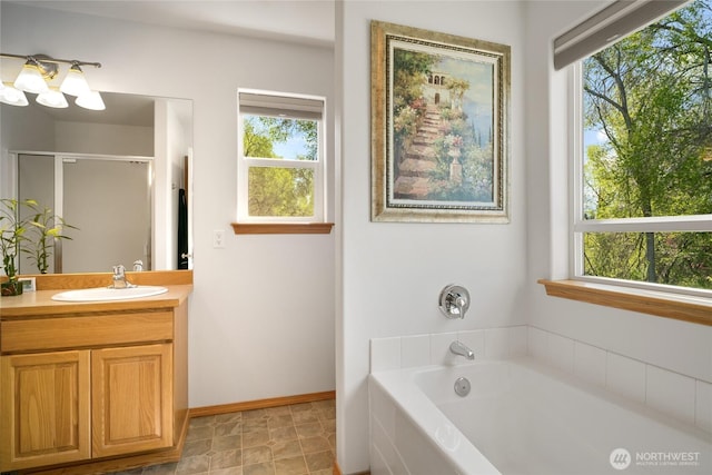full bath featuring a stall shower, a garden tub, vanity, and plenty of natural light