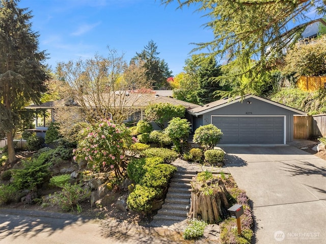 view of front of property with fence, an attached garage, driveway, and stairs