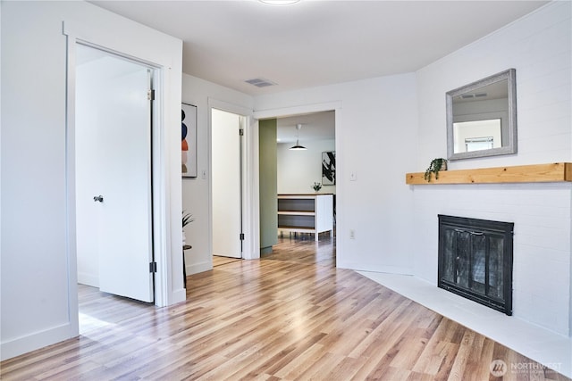 unfurnished living room with light wood finished floors, a fireplace with flush hearth, and baseboards