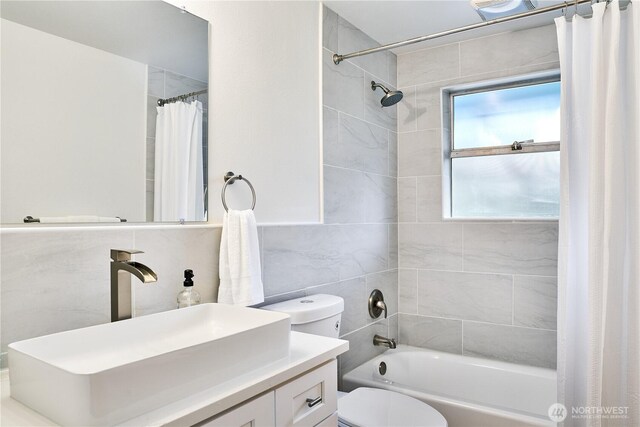 full bath featuring toilet, shower / tub combo with curtain, vanity, and tile walls