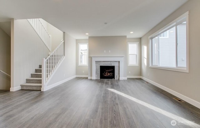 unfurnished living room with baseboards, stairway, wood finished floors, and visible vents