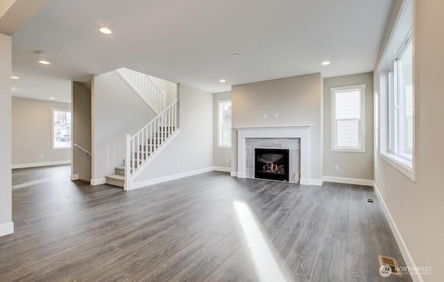 unfurnished living room with dark wood finished floors, stairway, a glass covered fireplace, and baseboards