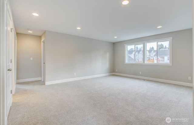 empty room featuring baseboards, recessed lighting, and light carpet