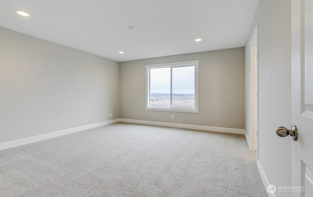 empty room featuring light colored carpet, recessed lighting, and baseboards