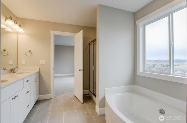 bathroom featuring a shower stall, a sink, double vanity, baseboards, and a bath