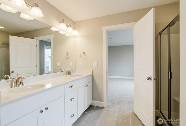 bathroom featuring tile patterned floors, a stall shower, double vanity, and a sink