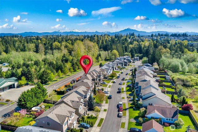 birds eye view of property featuring a view of trees, a mountain view, and a residential view