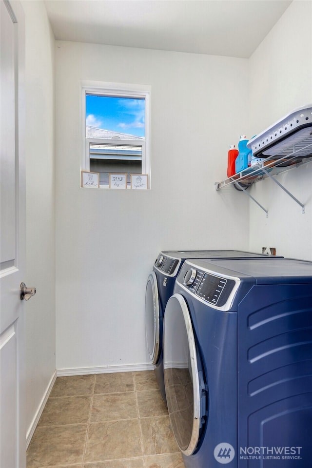 washroom featuring washing machine and clothes dryer, baseboards, and laundry area