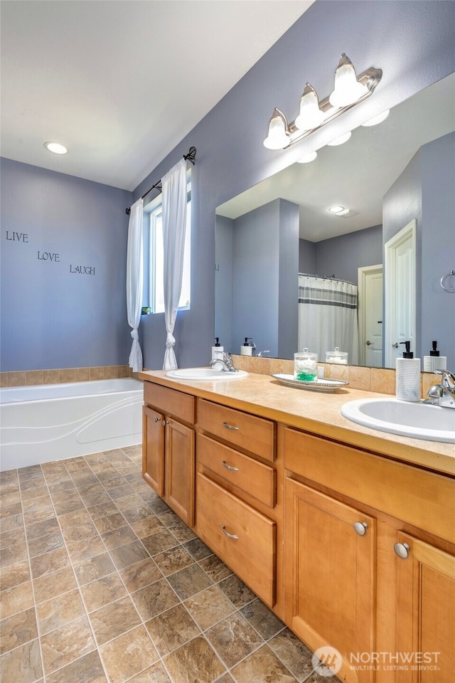 bathroom with a bath, a sink, double vanity, and stone finish flooring