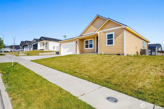 view of front of property featuring an attached garage, concrete driveway, central AC, and a front yard