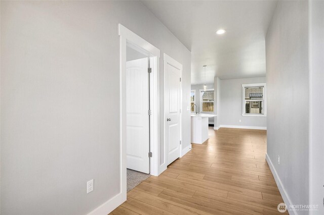 corridor featuring recessed lighting, baseboards, and light wood finished floors