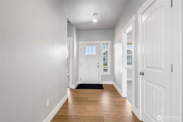 doorway featuring wood-type flooring and baseboards