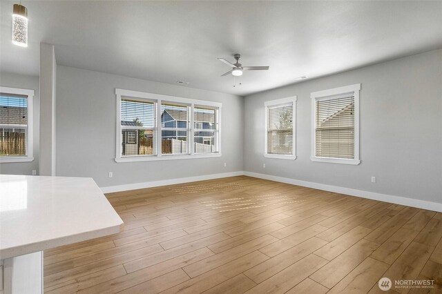 unfurnished living room with baseboards, a ceiling fan, and wood finished floors