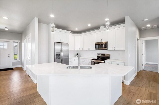 kitchen featuring light wood-style floors, a sink, appliances with stainless steel finishes, and light countertops