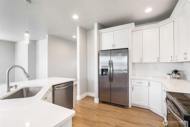kitchen with light countertops, a sink, white cabinets, and stainless steel appliances