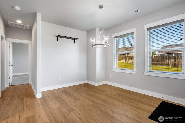 unfurnished dining area featuring baseboards, light wood-type flooring, and visible vents