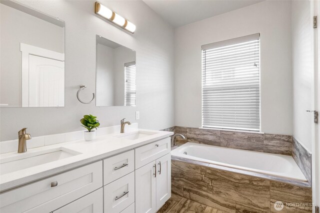 bathroom featuring a garden tub, a sink, and double vanity