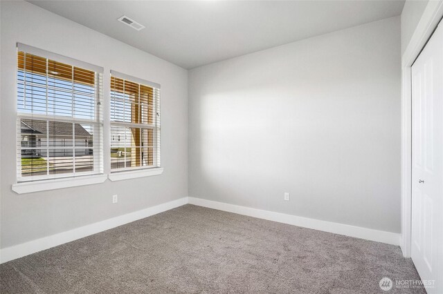 spare room featuring carpet flooring, baseboards, and visible vents