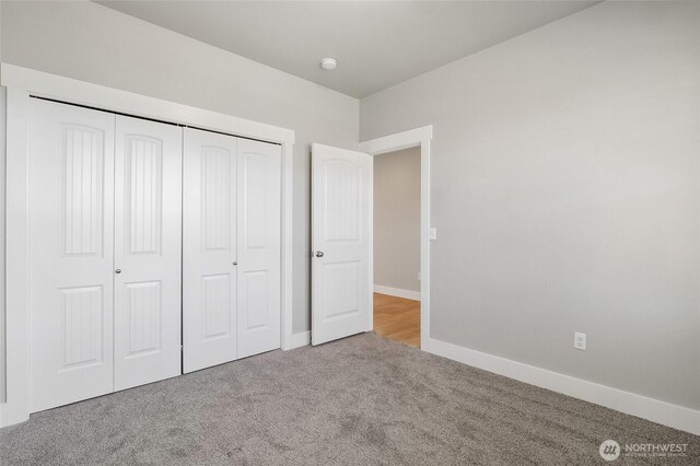 unfurnished bedroom with baseboards, carpet flooring, and a closet
