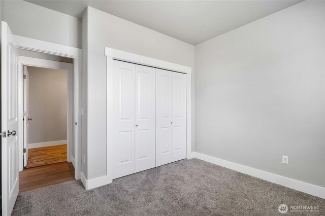 unfurnished bedroom with a closet, baseboards, and carpet flooring