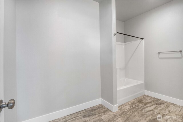 bathroom featuring baseboards and  shower combination