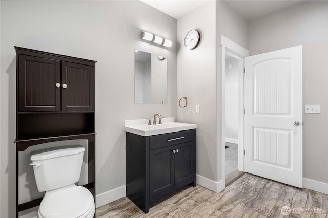 bathroom with toilet, baseboards, marble finish floor, and vanity