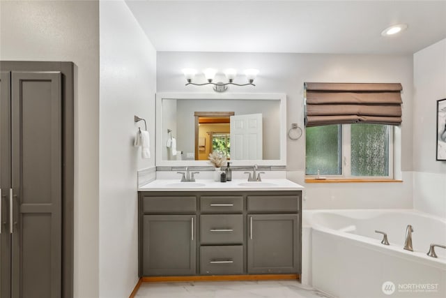 full bath featuring a garden tub, a sink, recessed lighting, and double vanity