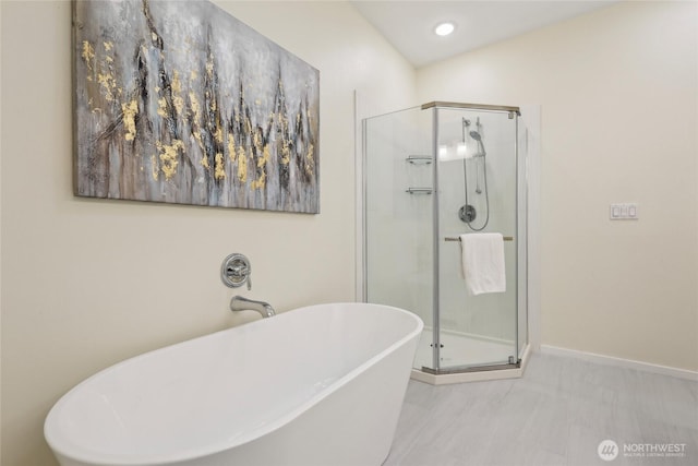 full bath featuring a freestanding bath, a shower stall, baseboards, and recessed lighting