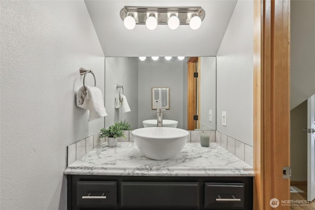 bathroom featuring a textured wall and vanity