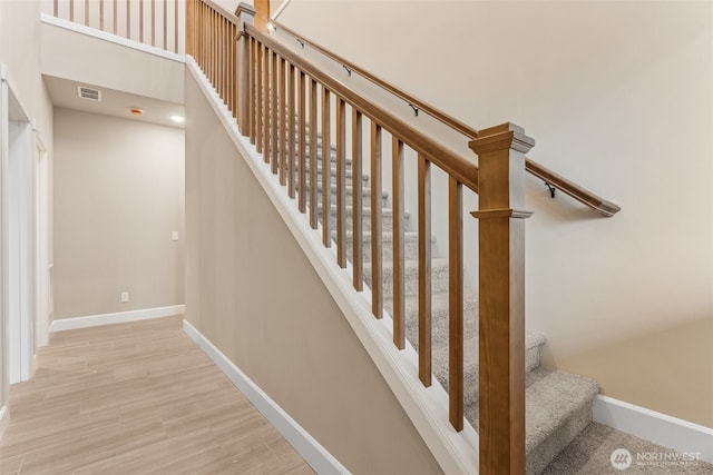 stairway featuring wood finished floors, visible vents, and baseboards