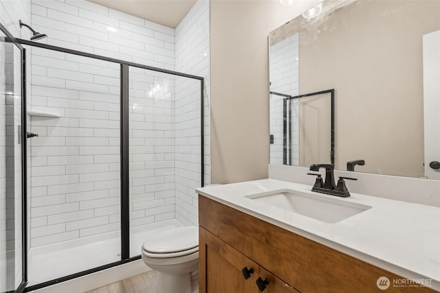 bathroom featuring toilet, a shower stall, wood finished floors, and vanity