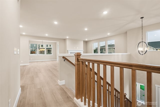 corridor with recessed lighting, light wood-style floors, an upstairs landing, a notable chandelier, and baseboards
