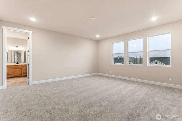 unfurnished bedroom featuring baseboards, recessed lighting, light carpet, and ensuite bath