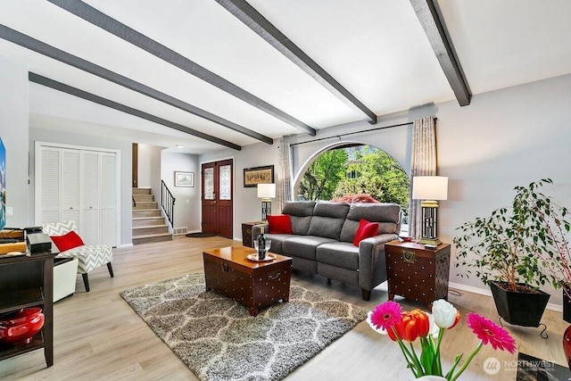 living room with beamed ceiling, baseboards, stairway, and light wood-type flooring
