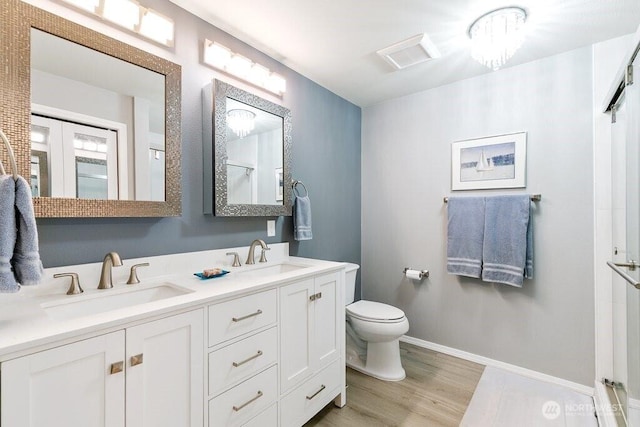 bathroom with double vanity, a sink, wood finished floors, and toilet