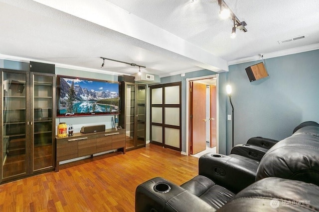 cinema featuring visible vents, rail lighting, a textured ceiling, and wood finished floors