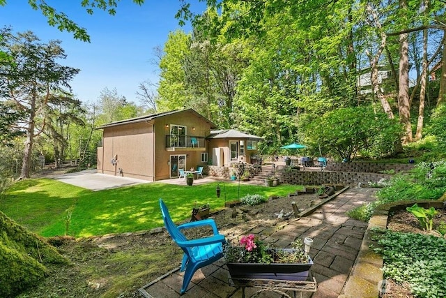 back of house featuring a patio, stucco siding, a yard, and a balcony