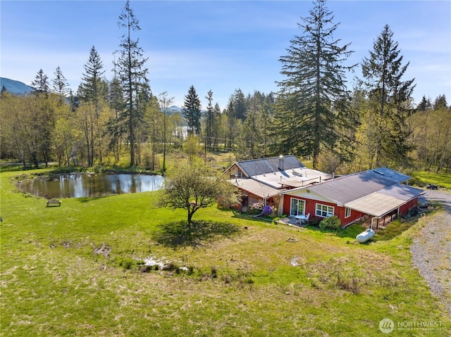 drone / aerial view with a wooded view and a water view