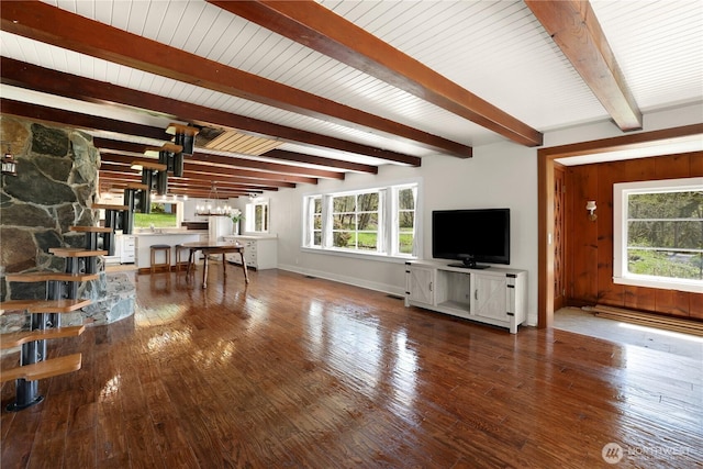living room with a chandelier, hardwood / wood-style flooring, beam ceiling, and plenty of natural light